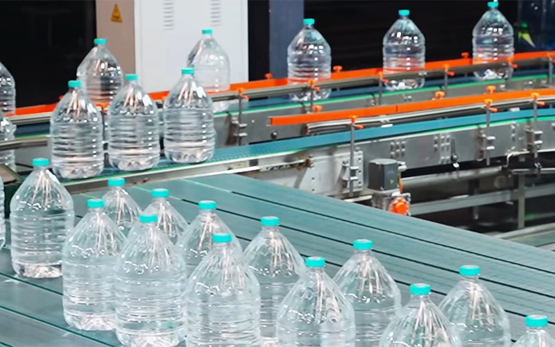 Operators managing a fully automated 3-10L water bottling line with capping system