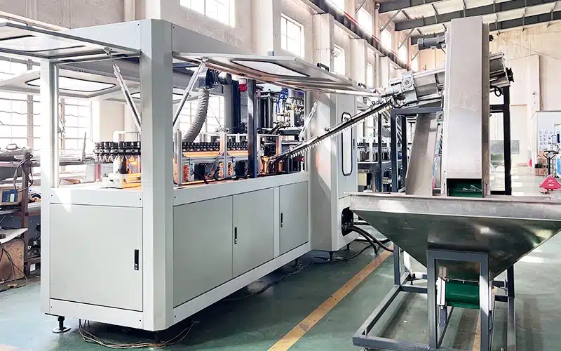 Automatic 4-cavity PET bottle blowing machine producing plastic bottles at high speed.