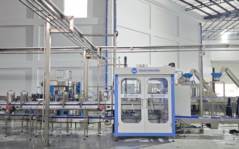 A complete filling line installed by NAVAN Africa CO.,LTD, showing stainless steel conveyors and filling nozzles in action.