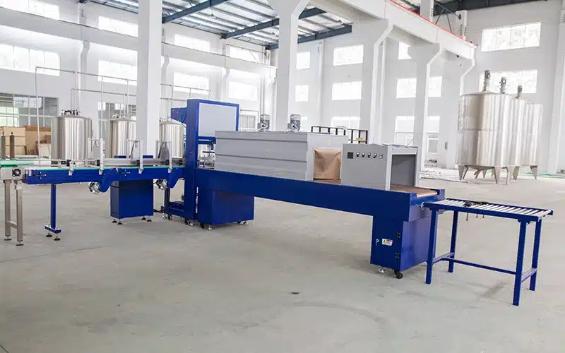Automatic PE film wrapping machine bundling water bottles into multi-packs for shipping.
