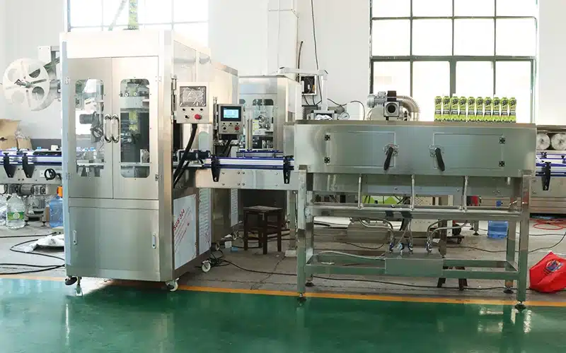 Automatic shrink sleeve labeling machine applying full-body labels to water bottles.