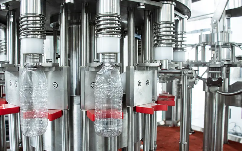 Close-up of non-drip stainless steel filling valves on a bottled water filling machine