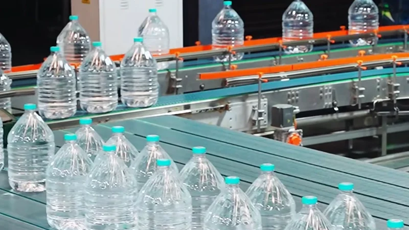 Operators managing a fully automated 3-10L water bottling line with capping system