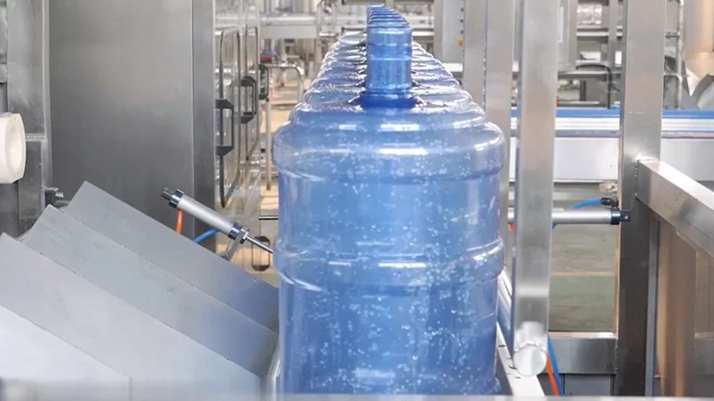 Operators working with 5 gallon water bottle filling machine in production line
